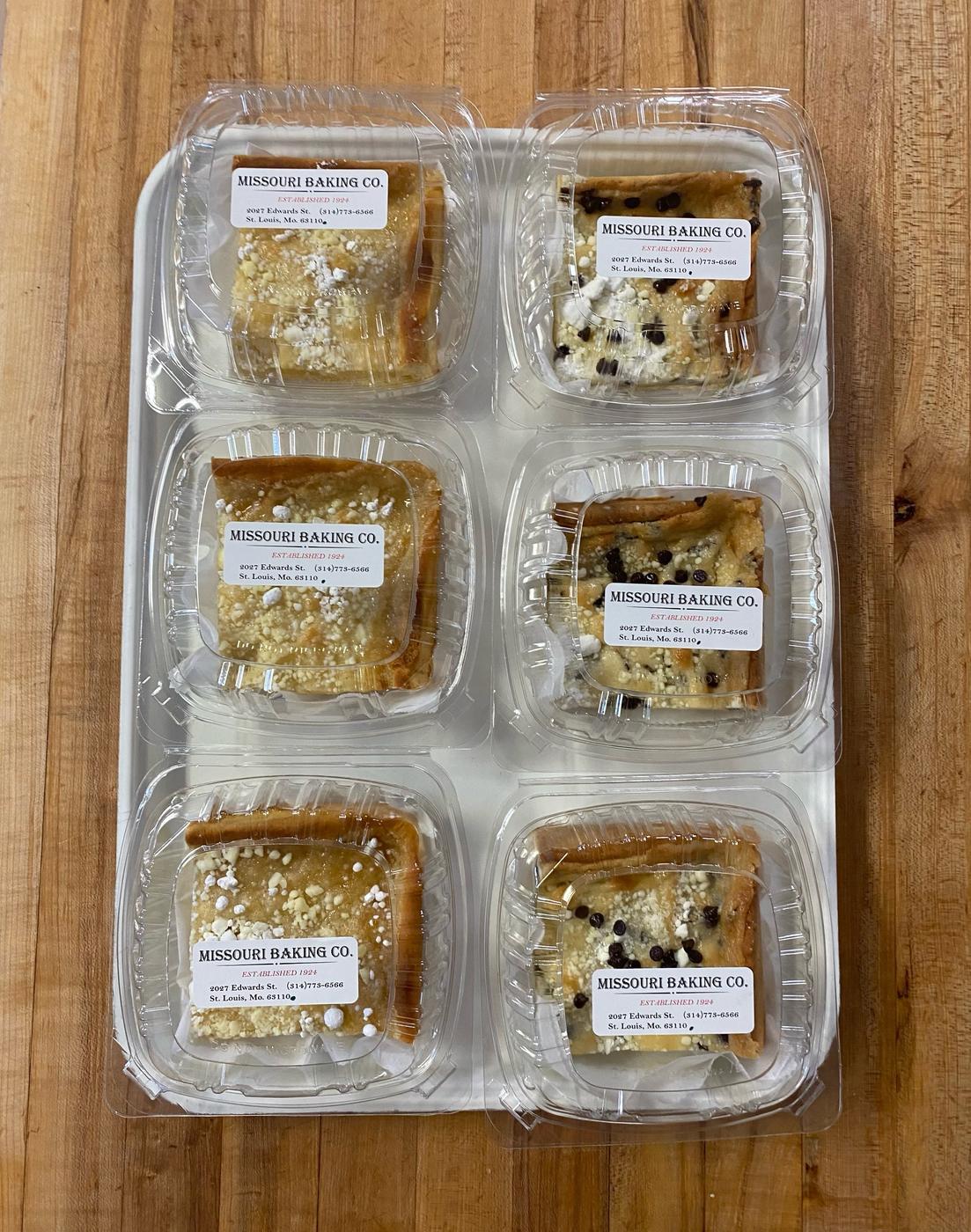 Six boxed pieces of gooey butter cake on a butcher block, each carrying a printed Missouri Baking Co label reading Established 1924, 2027 Edwards St